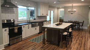 Une cuisine moderne avec des meubles blancs, des appareils en acier inoxydable et un îlot central en bois.