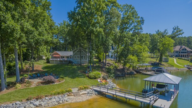 Une propriété au bord du lac, dotée d’un quai, d’un belvédère et d’une grande maison entourée d’arbres.