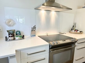 A modern kitchen with a built-in stove, stainless steel cabinets, and a range hood.
