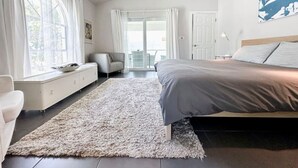A bedroom with a bed, a sofa, a window with curtains, a ceiling fan, and a view of the outdoors. - The Pop Hauz - Large Pool House (Naples)