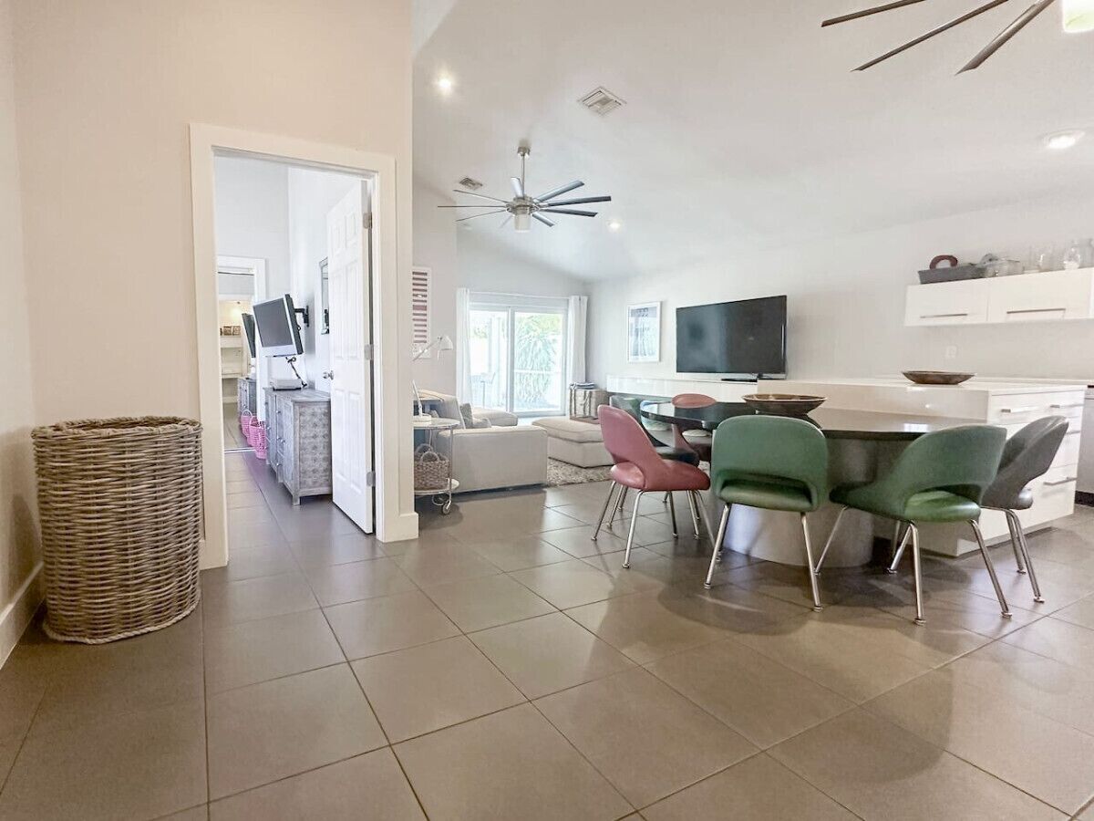 A spacious living area with a dining table, chairs, a television, and a kitchen area.