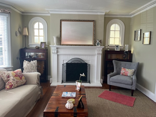 Una sala de estar con chimenea, un sofá, un sillón y una mesa de centro.