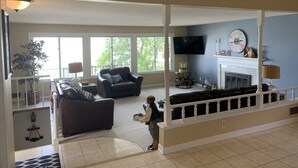 Un salón espacioso con chimenea, televisor montado en la pared y un ventanal que proporciona luz natural.