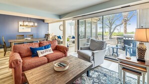Un salón amplio con un gran ventanal corredera que da a un patio exterior.