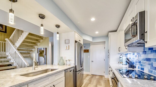 Una cocina moderna con armarios blancos, un refrigerador de acero inoxidable y un salpicadero con azulejos azules.