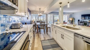 Una cocina moderna con una isla central, electrodomésticos de acero inoxidable y un amplio ventanal que proporciona luz natural.