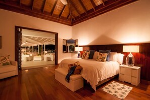 A spacious bedroom with a large bed, a nightstand, a chair, and a sofa. There is a wooden ceiling and a large mirror on the wall. - Allamanda Villa- Tryall Resort Membership- van/driver- nanny  (Montego Bay,)