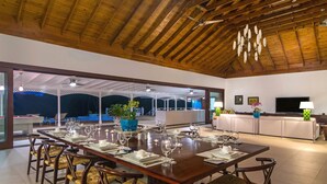 Un vaste espace dédié à la salle à manger, avec une longue table en bois pouvant accueillir six personnes, entourée de chaises en osier.