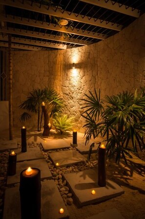 A stone-walled room with a ceiling fan, candles, and tropical plants. - Allamanda Villa- Tryall Resort Membership- van/driver- nanny  (Montego Bay,)