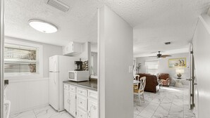 Una cocina moderna con armarios blancos y un refrigerador blanco.