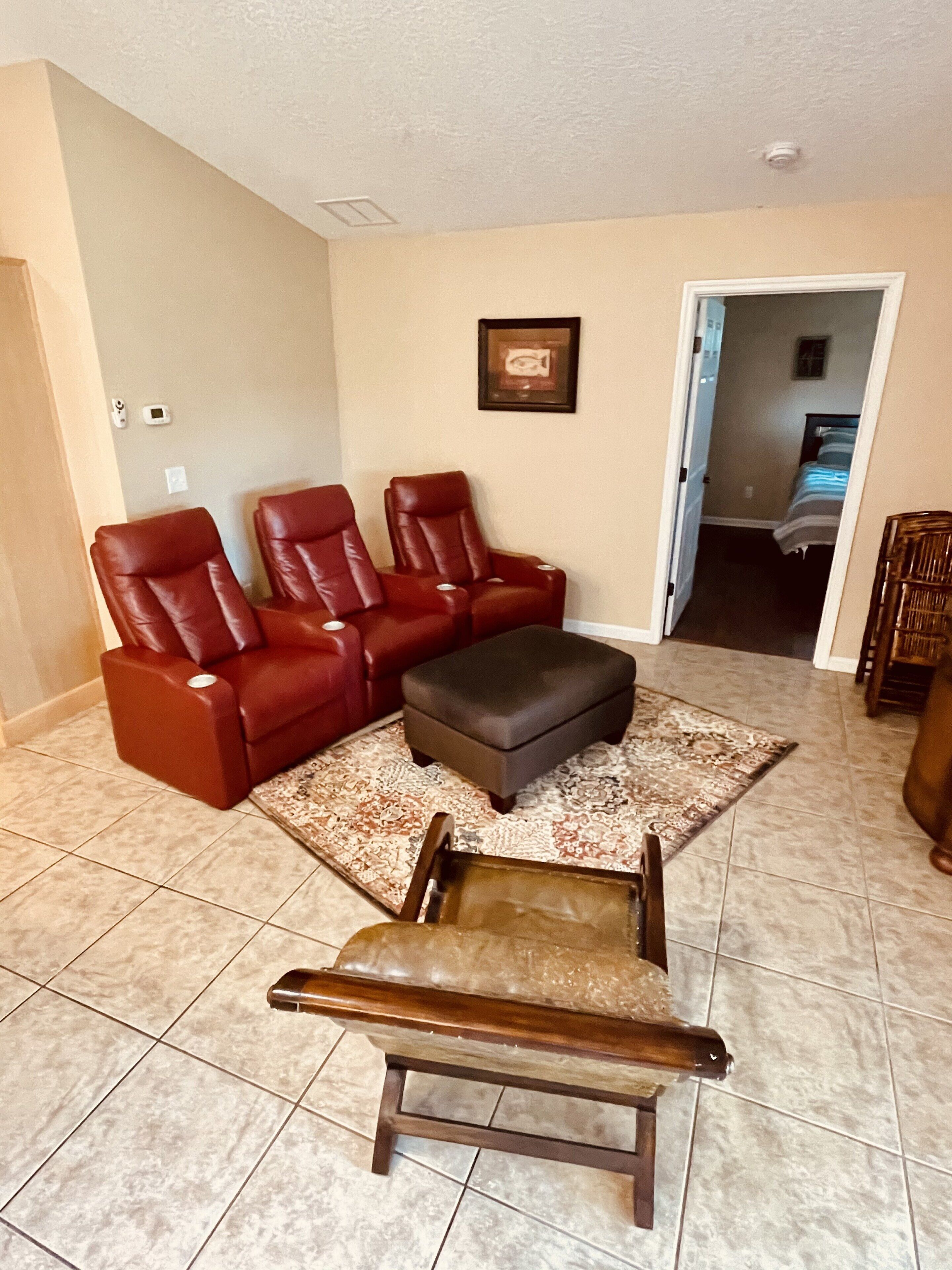 A living room with a brown leather sofa, a matching ottoman, and a wooden coffee table.