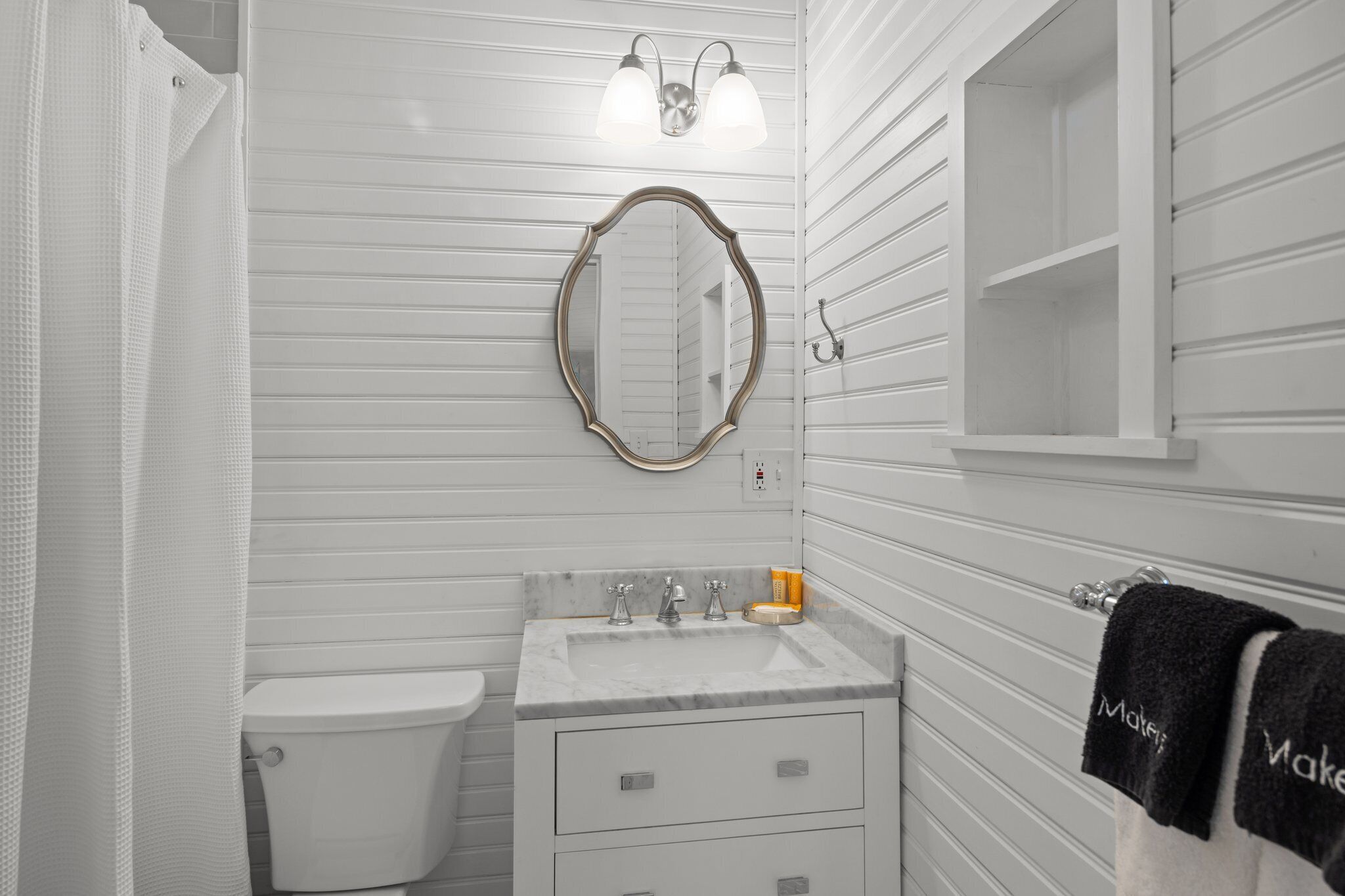 Une salle de bain avec des toilettes, un lavabo et un miroir. On y trouve également un porte-serviettes avec des serviettes.
