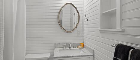 Une salle de bain avec des toilettes, un lavabo et un miroir. On y trouve également un porte-serviettes avec des serviettes.