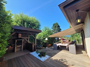 A wooden deck with a barbecue area, outdoor seating, and a pergola. - Spacious Lake Annecy Villa - Delightful in Summer or Winter  (Menthon-Saint-Bernard)