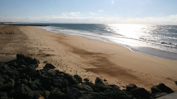 Ein Strand mit einem felsigen Vordergrund und freiem Blick auf den Ozean.
