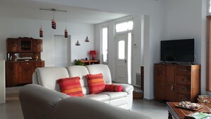 Ein Wohnzimmer mit einem weißen Sofa, einer Holzkommode und einem Fernseher.
