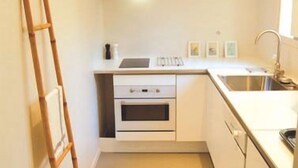 A compact kitchen with white cabinetry, a stainless steel sink, and a built-in oven. - Accommodation near the sea with 100m2 fenced garden. Closed private parking with beeper. (La Ciotat)