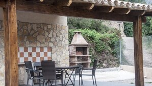 Um pátio externo com parede de pedra, forno de tijolos e estrutura de pérgola.
