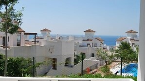 A coastal residential area with white buildings, some with red-tiled roofs, and a clear view of the sea. - Apartment  in Alcaidesa (Alcaidesa)