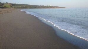 A beach with a lighthouse on a hill in the distance. - Apartment  in Alcaidesa (Alcaidesa)