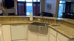 Uma cozinha moderna com bancadas de granito, armários brancos e lava-louças embutida.