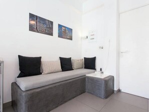 A modern room with a grey sofa, a small table, and two framed pictures on the wall.