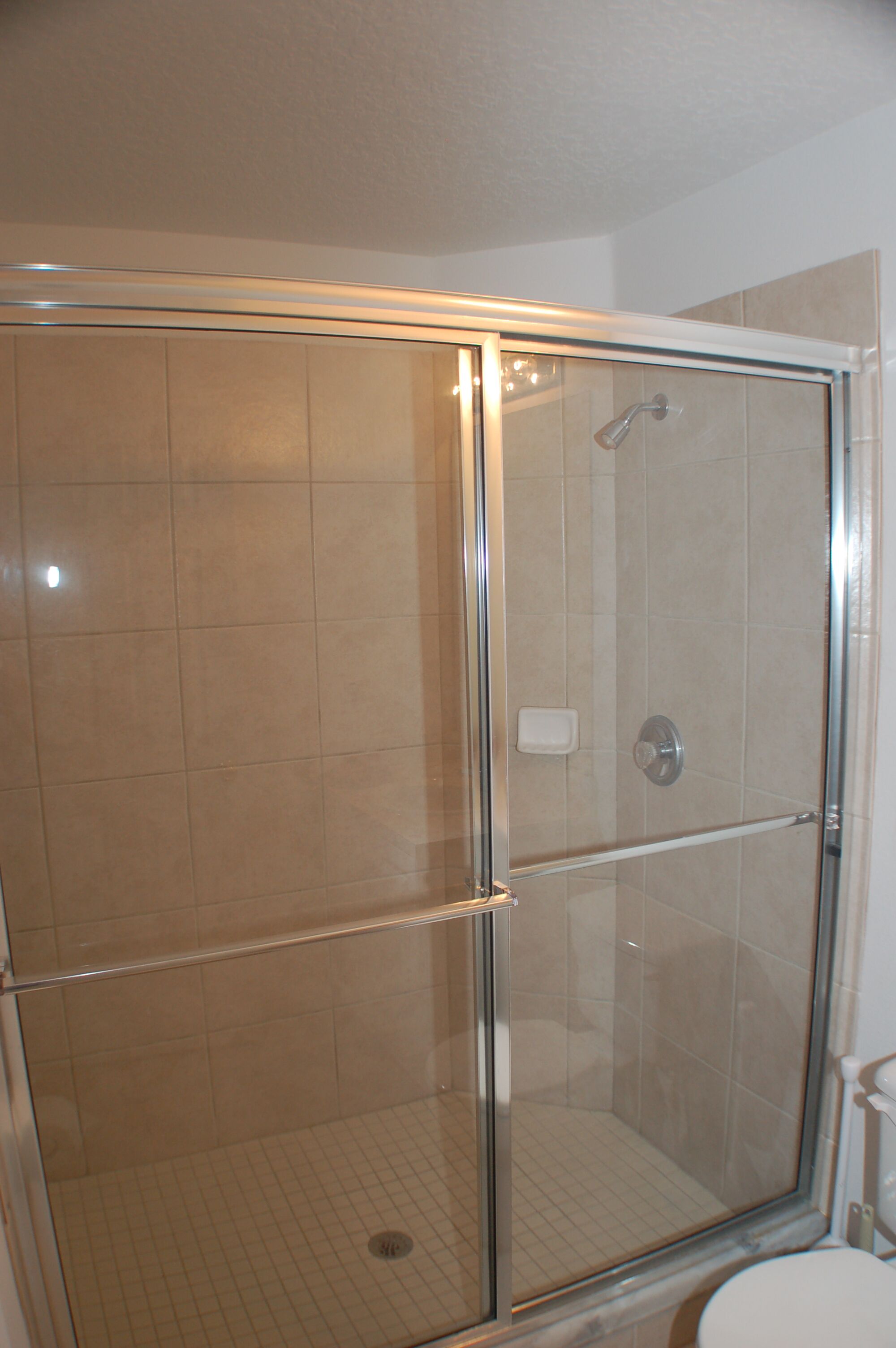 A glass-enclosed shower with a tiled floor and a visible drain.