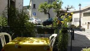 Ein Tisch mit gelber Tischdecke und Stühlen, eine Straße mit Autos und ein Gebäude mit einer blauen Schilder.