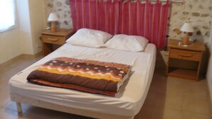 Ein Schlafzimmer mit einem Bett, zwei Nachttischen mit Lampen, einem Fenster und einer Wand mit Steinmuster.