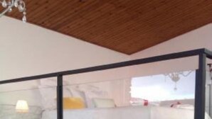 Ein Schlafzimmer mit einem Bett, einem Nachttisch und einem kleinen Tisch. Es gibt ein Fenster mit Blick nach draußen.