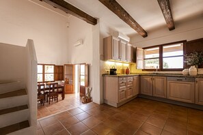 A kitchen with wooden cabinets, a dining area with a table and chairs, and a staircase leading to another level.