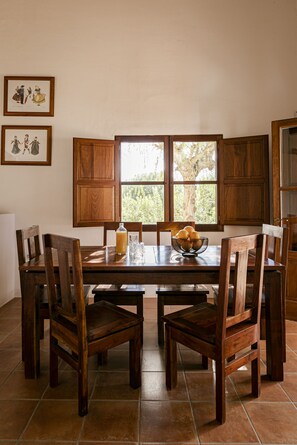 Un comedor con una mesa de madera, sillas y una ventana con vistas a árboles.