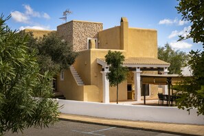 Un edificio con fachada de piedra, techo plano y una zona de estar al aire libre cubierta.