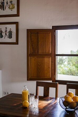 A wooden dining table with a glass bottle, a glass, and a fruit basket. - Well-equipped house with an unbeatable central location (Sant Francesc de Formentera)