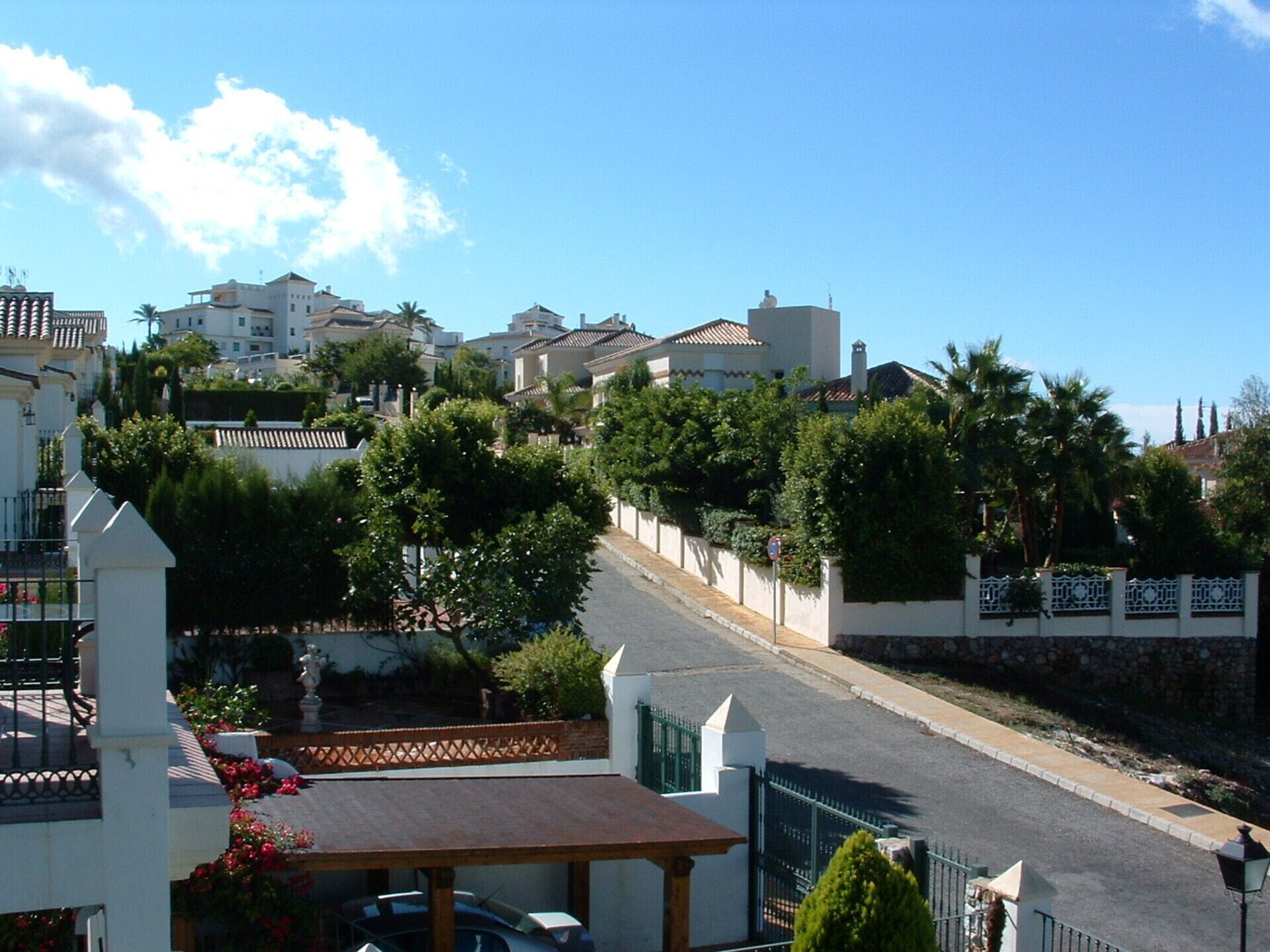 Une rue résidentielle bordée de maisons, avec une entrée sécurisée et un ciel dégagé.