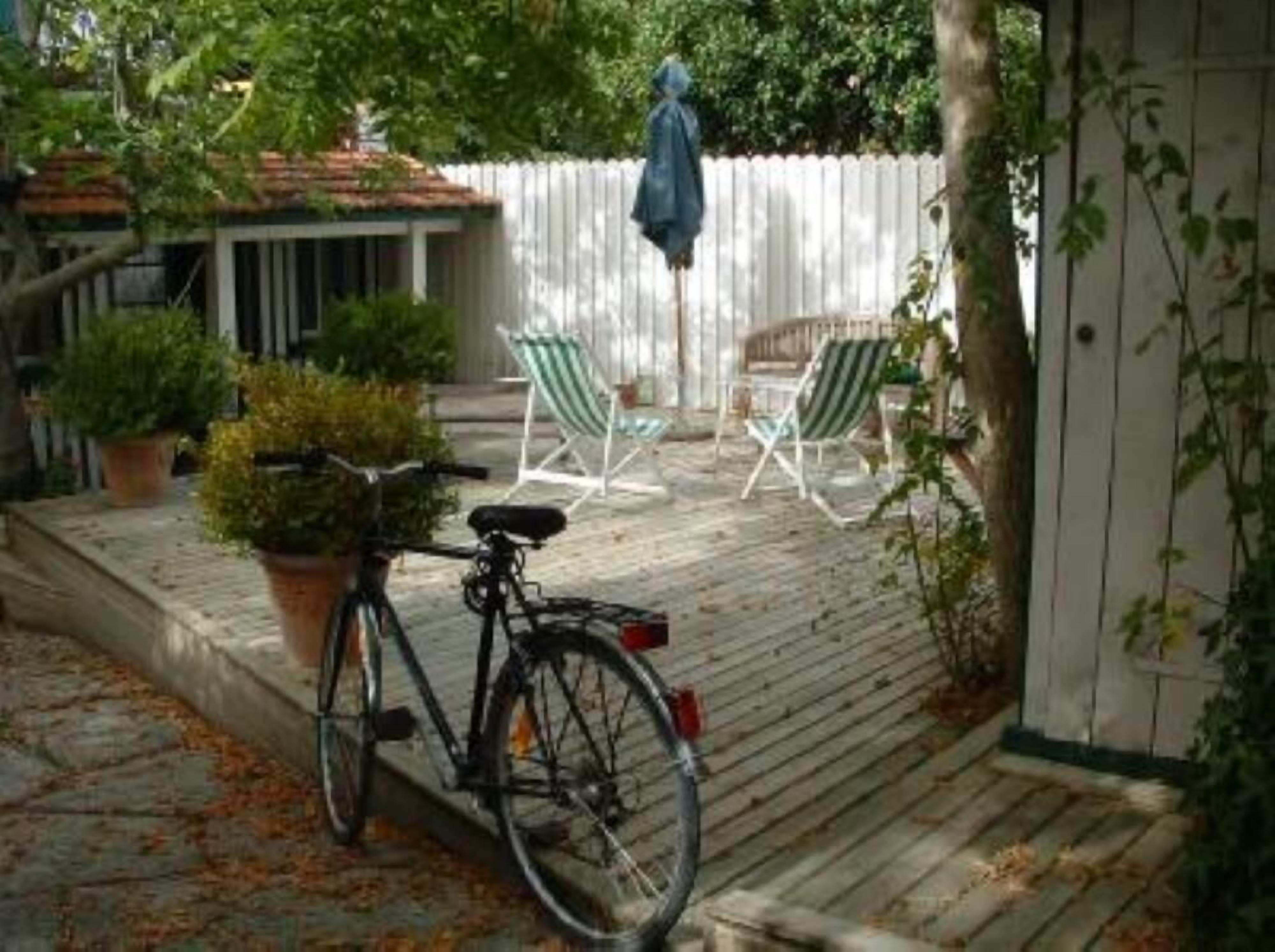 Eine Holzterrasse mit einem Fahrrad, Topfpflanzen und Gartenmöbeln.