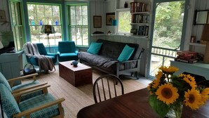 Uma sala de estar aconchegante com um sofá, cadeiras, uma mesa de centro e uma estante de livros.