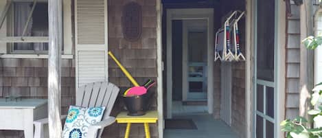 A porch with a wooden chair, a small table, and a door leading to a room.