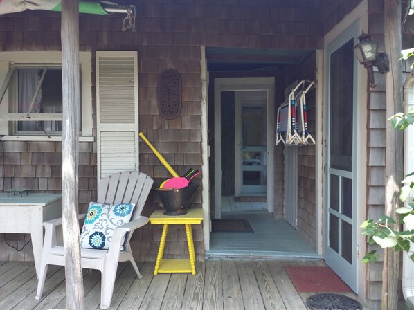 A porch with a wooden chair, a small table, and a door leading to a room.
