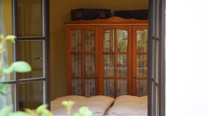 A room with a bed, a wooden cabinet with glass doors, and a window. - Lovingly furnished vacation apartment with sunny, quiet balcony facing the lavender (Freital)