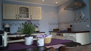 A kitchen with white cabinets, a stove, and a dining table with chairs. - Lovingly furnished vacation apartment with sunny, quiet balcony facing the lavender (Freital)