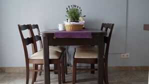 A dining table with a purple tablecloth, four wooden chairs, a wicker basket with a plant, and a white mug. - Lovingly furnished vacation apartment with sunny, quiet balcony facing the lavender (Freital)