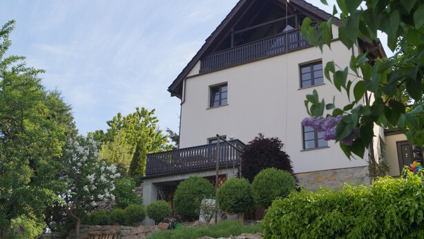 A two-story building with a balcony, surrounded by well-maintained gardens and stone walls. - Lovingly furnished vacation apartment with sunny, quiet balcony facing the lavender (Freital)