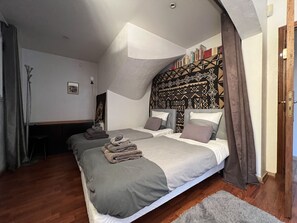 Ein Schlafzimmer mit zwei Betten, einem gemusterten Kopfteil und Holzboden.