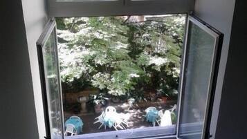 Ein Zimmer mit einem großen Fenster mit Blick auf einen Garten.