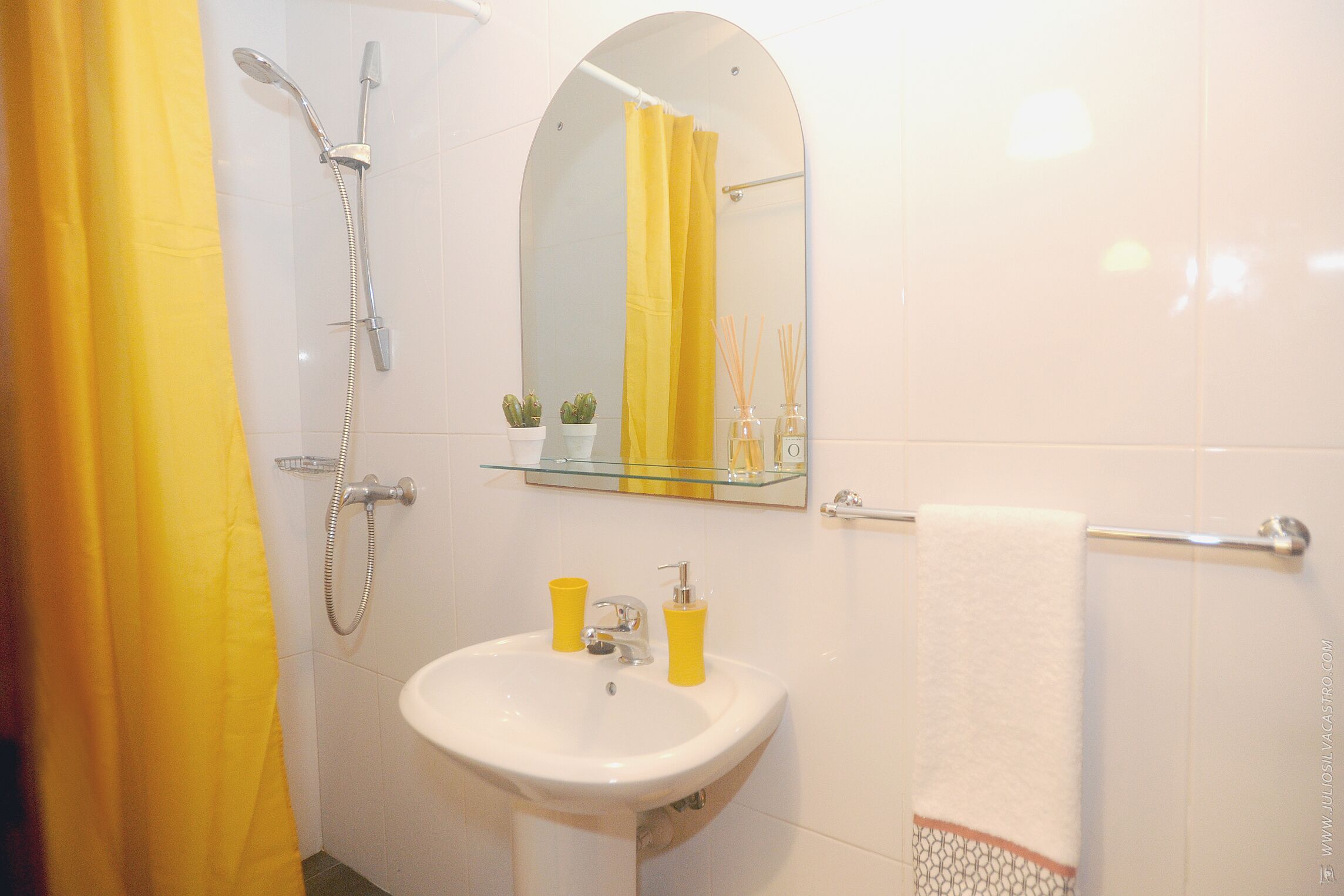 Une salle de bain équipée d’une douche, d’un lavabo, d’un miroir et d’un porte-serviettes.