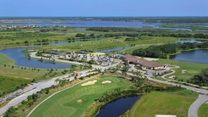 Un campo de golf con varios cuerpos de agua, un club de campo y abundante vegetación circundante.