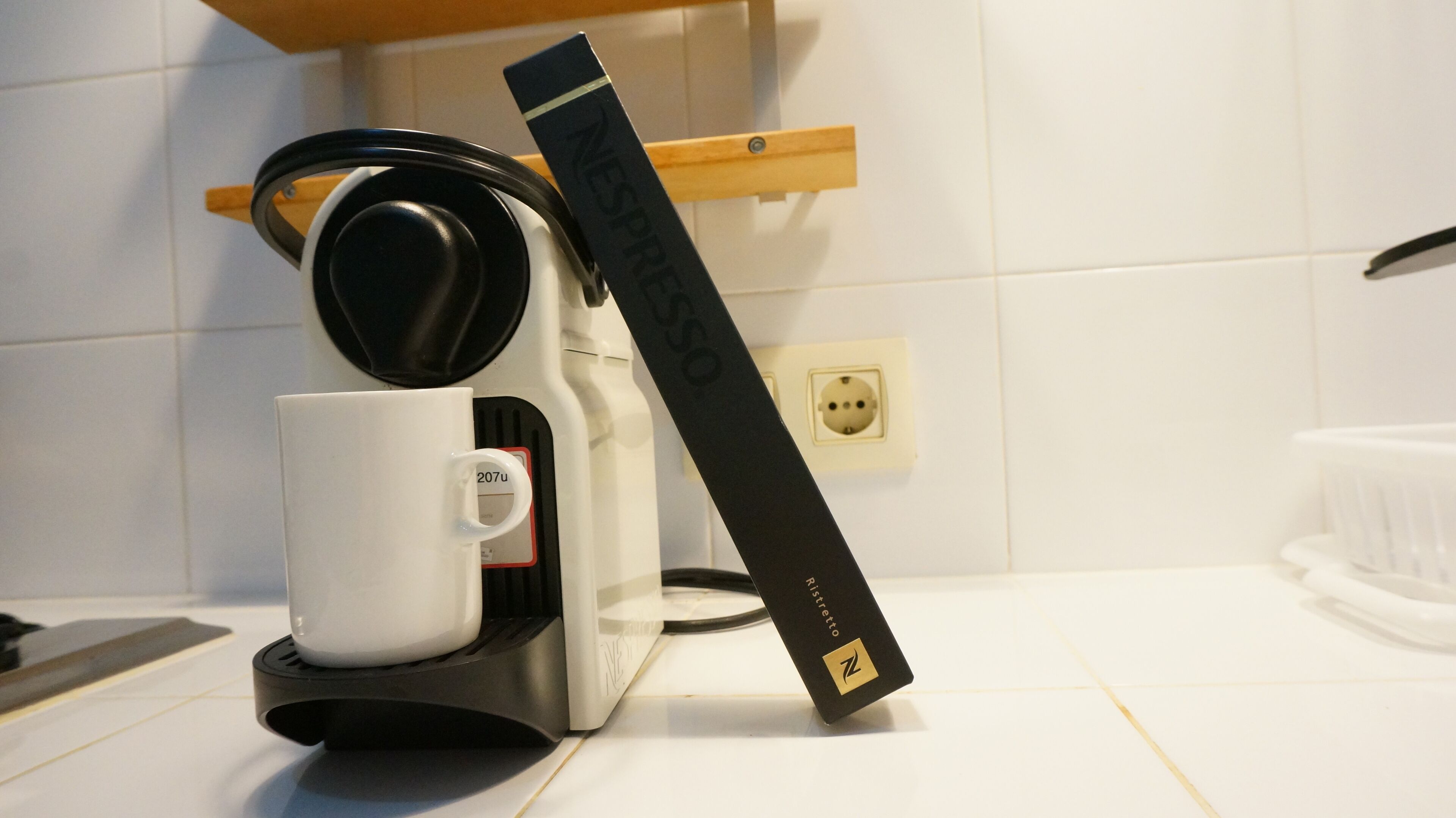 A coffee maker with a white mug and a Nespresso pod holder.