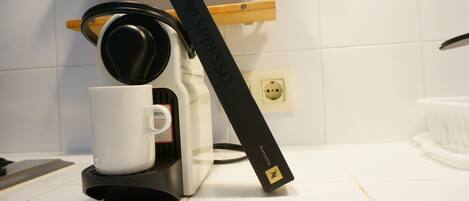 A coffee maker with a white mug and a Nespresso pod holder.