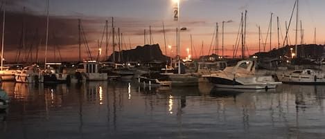 En marina i skumringen med tilkoblede både og en gadelampe.